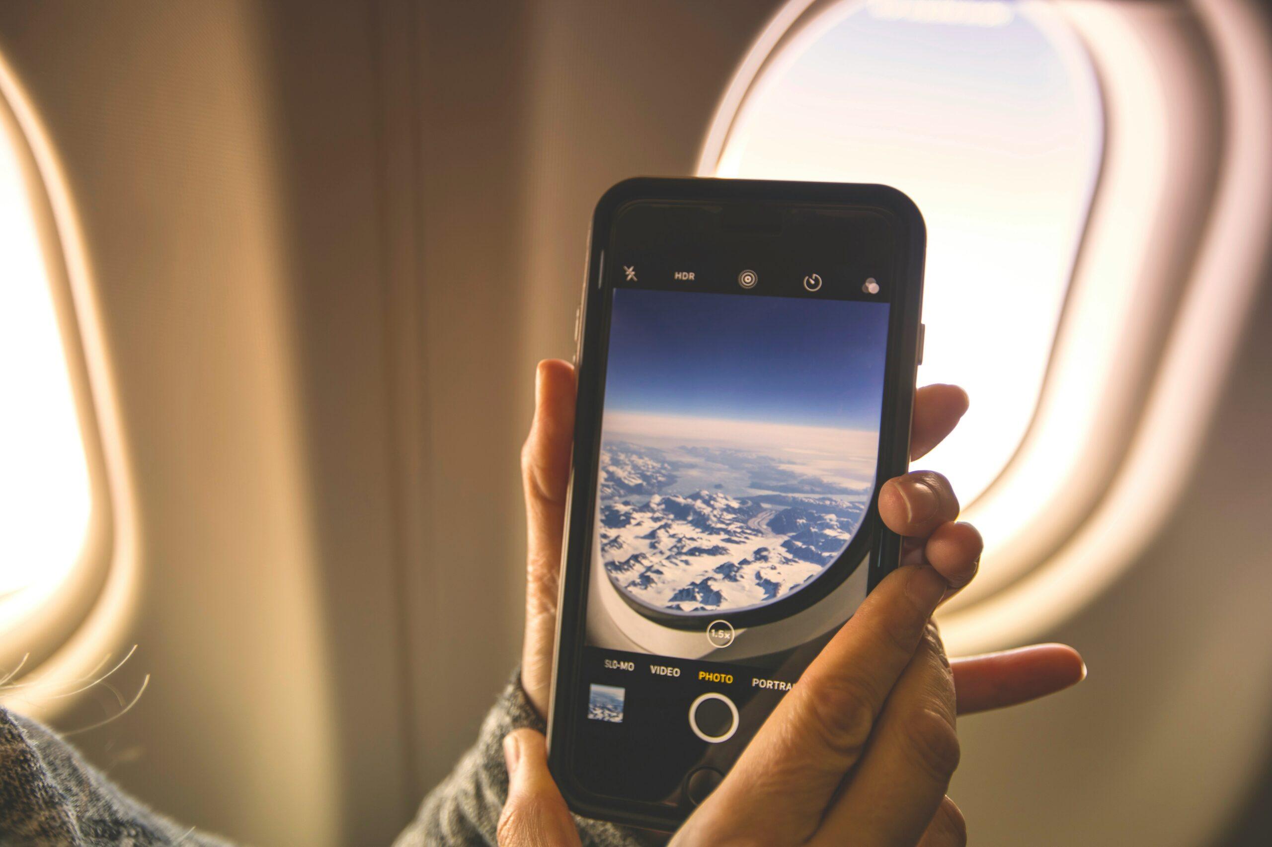 Photo of happy traveler holding smartphone displaying itinerary protection app interface next to luggage.