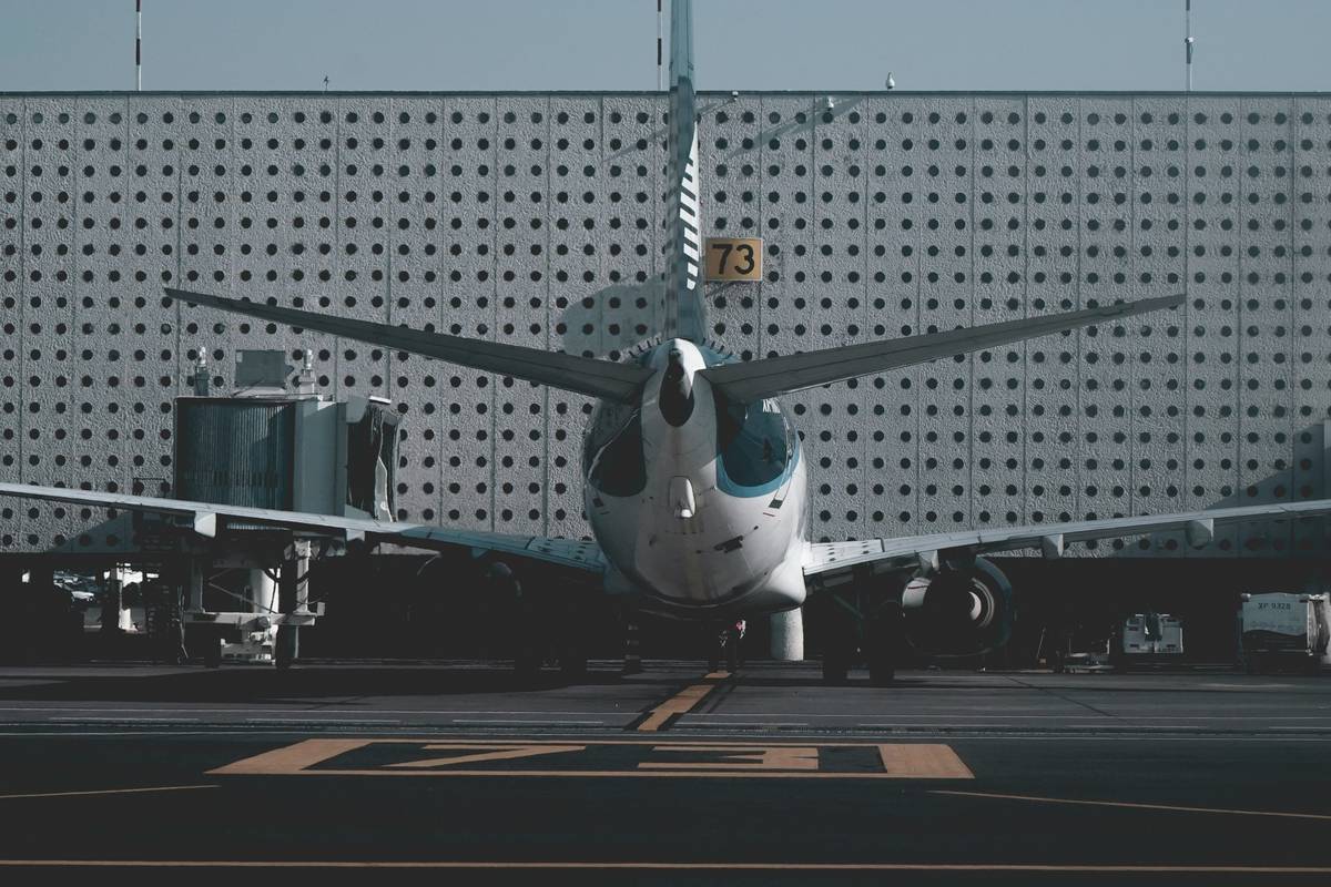 A frustrated traveler at an airport with a delayed flight sign in the background